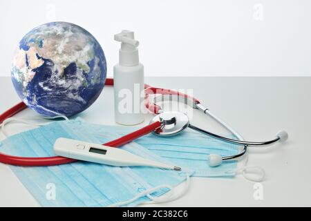 COVID-19. Globo mondiale con stetoscopio, maschere mediche, disinfettante, termometro su sfondo bianco. Quarantena globale, prevenzione delle infezioni, coronaviru Foto Stock