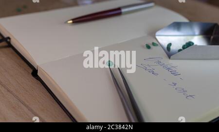 Pietra smeraldo su un notebook con note, clip di gioielli e penna Foto Stock