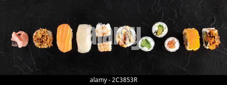 Sushi set, colpo panoramico in alto su uno sfondo nero. Una varietà di maki, nigiri e panini, con pesce e verdure Foto Stock