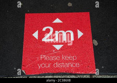 Un cartello sociale di 2 m sul pavimento a Cardiff, Galles, Regno Unito, durante il periodo di blocco del coronavirus. Foto Stock