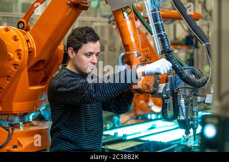 robotizzazione dell'industria moderna in fabbrica. Introduzione di nuovi bracci robotici per sostituire le risorse umane. Foto Stock