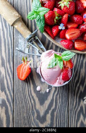 Gustoso gelato alla fragola con fragole fresche su sfondo di legno scuro. Messa a fuoco selettiva, spazio di copia Foto Stock