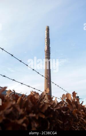 Vecchio camino in mattoni lungo con le parole Ristorante contro cielo blu, vecchia fabbrica industria con filo spinato Foto Stock