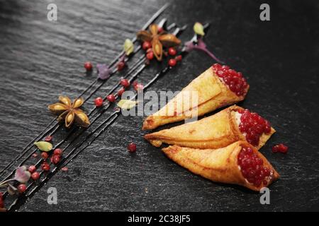 Pate di coniglio in corni croccanti decorato con spezie su un piatto di pietra nera Foto Stock