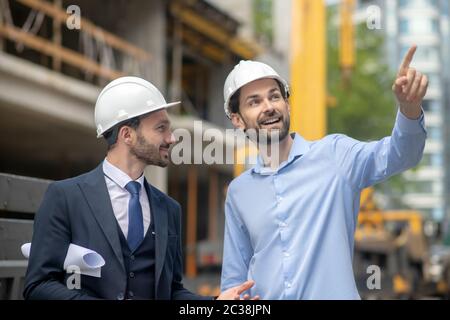 Cantiere. Caposquadra che punta la mano, mostrando qualcosa al supervisore della costruzione Foto Stock