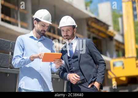 Cantiere. Caposquadra che mostra qualcosa al supervisore della costruzione sul suo tablet Foto Stock