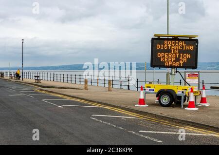 West Kirby, UK: 3 giugno 2020: A Marine Lake, un cartello illuminato temporaneo incoraggia i pedoni a mantenere la distanza sociale dovuta al virus corona Foto Stock