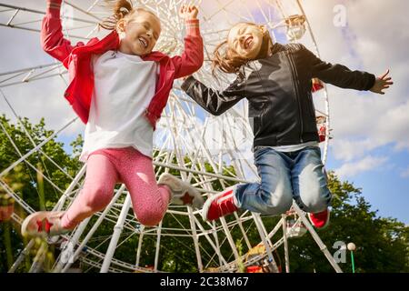 Due ragazze si divertono nel parco divertimenti. Una ruota panoramica è sullo sfondo. Foto Stock