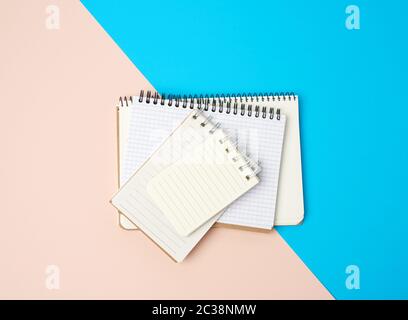 pila di notebook aperti a spirale con fogli bianchi vuoti su sfondo blu, vista dall'alto Foto Stock