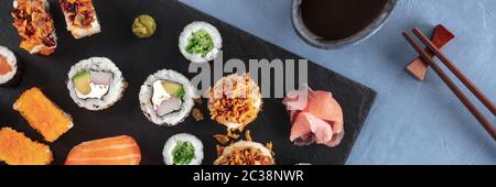 Ampio panorama sushi set con salsa di soia e bastoni, shot dalla cima. Una disposizione piana di vari maki, nigiri e rotoli Foto Stock