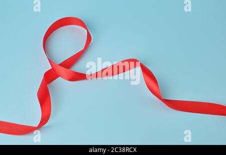 Seta rossa sottile nastro attorcigliato su uno sfondo blu, trendy classic colore, close up Foto Stock