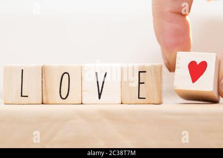 La parola amore su cubi di legno con cuore rosso, close-up vicino a sfondo bianco il concetto di san valentino Foto Stock