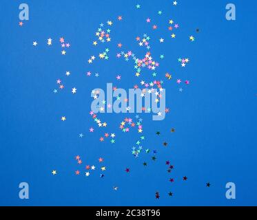 Lucido multicolore coriandoli a forma di stelle su uno sfondo blu, sfondo festosa modello. Luminose decorazioni di festa Foto Stock