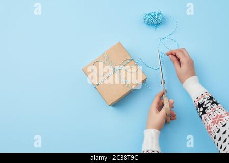 Gift Wrapped e legato con una corda marrone, femmina lato con le forbici taglia una corda marrone, congratulazioni concetto, spazio di copia Foto Stock