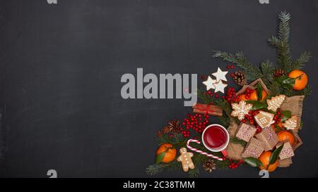 Ferme: Bacche, mandarini con foglie su vassoio di legno, tè alla frutta su tazza rossa, scatole regalo, spezie e rami di abete su sfondo scuro. V. Superiore Foto Stock