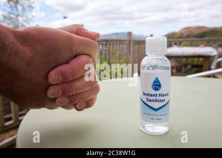 Un uomo usa una bottiglia di disinfettante per le mani per disinfettare le mani durante la pandemia di Covid-19. Foto Stock