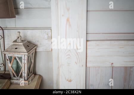 lanterna di legno verniciata bianca vecchia vernice che si stacca vintage, in piedi sul tavolo, accanto ad una vecchia lampada marrone con una tonalità marrone Foto Stock