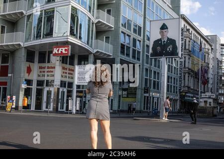 Una donna scatta una foto al Checkpoint Charlie sulla Friedrichstrasse, il muro di Berlino che attraversa Berlino Est e Berlino Ovest durante la Guerra fredda. Foto Stock