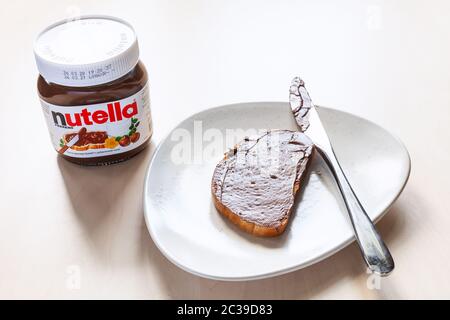 MOSCA, RUSSIA - 16 GIUGNO 2020: Vasetto di Nutella in vetro e toast con cacao alla nocciola dolcificato spalmato su piatto. Viene prodotta la spalmata Nutella Foto Stock