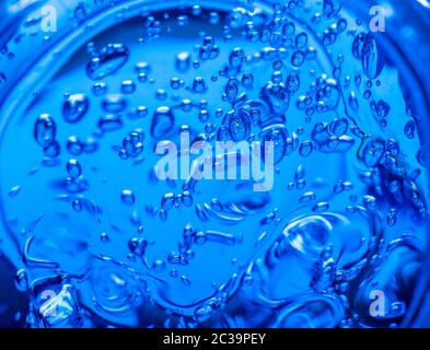 Gel liquido su uno schermo digitale di microscopio o acqua di scannonamento. Bolle di ossigeno in un bicchiere d'acqua su sfondo blu. Minera Foto Stock