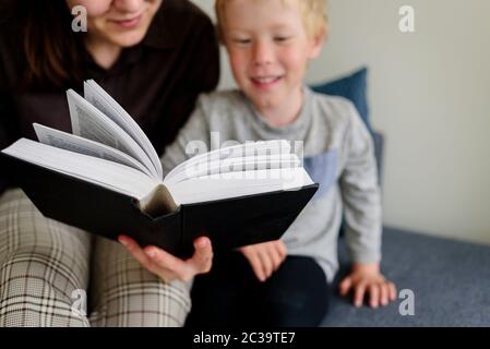Madre e bambino leggere libro e sorridere. Buon tempo in famiglia insieme Foto Stock