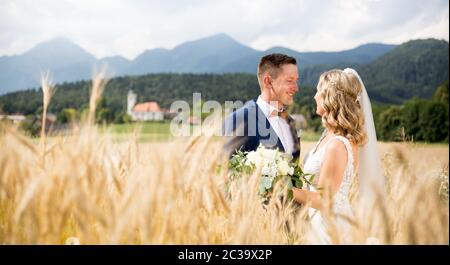 Bride brodere teneramente in campo di grano da qualche parte nella campagna slovena. Caucasica felice romantica giovane coppia celebrare il loro matrimonio. Foto Stock