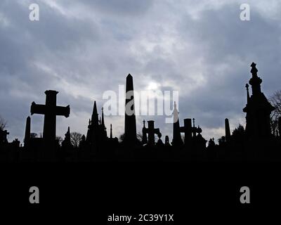 lapide in stile gotico antico con alto memoriale e croci contro un cielo nuvoloso sovrastato Foto Stock