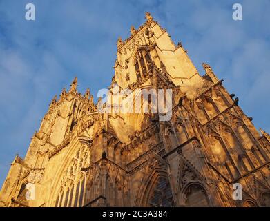 una vista frontale delle torri all'ingresso della cattedrale di york in luce solare contro un cielo blu nuvoloso Foto Stock