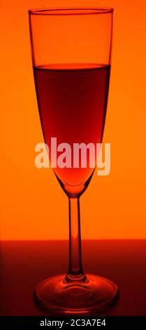 Vetro o stemware con alcool il vino,whiskey, gin,birra,rum,vodka,Scotch,cognac,liquor,brandy,assenzio o cocktail su uno sfondo arancione. Un vetro su th Foto Stock