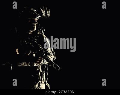 Esercito operazioni speciali forze soldato in maschera e uniforme da combattimento, casco dotato di dispositivo di visione notturna, armata mitragliatrice con silenziatore, guardando come Foto Stock