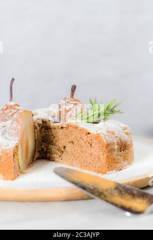 Deliziosa fetta di torta con pera, zenzero e cannella su un piatto in un bancone da cucina scuro. Foto Stock