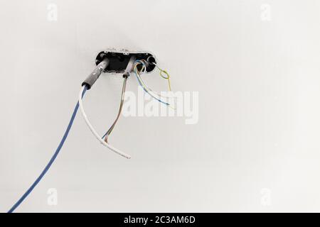 Informazioni di base sul cablaggio elettrico. Scatola elettrica e cavi su parete bianca. Cantiere interno. Spazio di copia Foto Stock