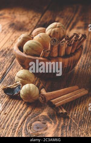 Bastoncini di cannella ed essiccato limes nella ciotola di legno sul tavolo rustico Foto Stock