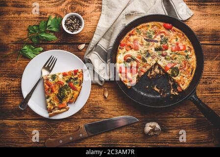 Frittata di verdure con broccoli, il peperone rosso e cipolla rossa sulla piastra bianca e in ghisa. Vista da sopra Foto Stock