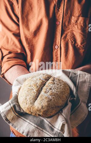 L'uomo detiene una pagnotta di pane appena sfornato pane di segale Foto Stock