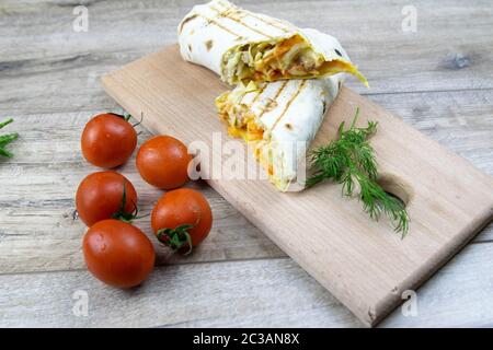 Pezzi di intagliate armeno sottile pane pita o lavash avvolto di pomodoro, formaggio o latticini, carne di pollo, pomodori e le erbe - aneto, cipolla, prezzemolo Foto Stock