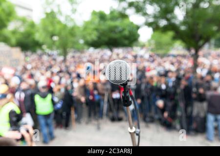 Protesta. Dimostrazione pubblica. Microfono a fuoco contro pubblico sfocata. Foto Stock