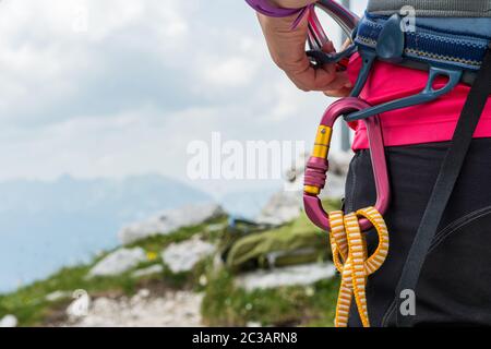 Donna irriconoscibile arrampicatore che indossa imbracatura di sicurezza con attrezzature per scalate e Quickdisks all'aperto. Foto Stock