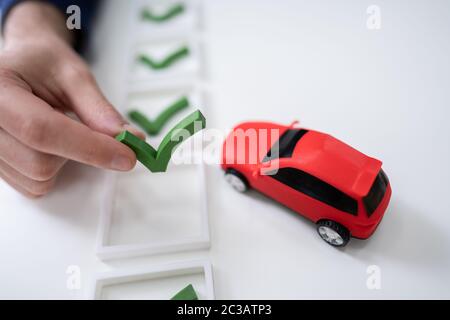 Mano umana ponendo Icona segno di spunta Puzzle vicino a piccole auto blu Foto Stock