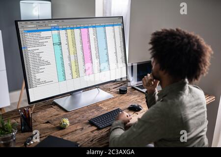 Close-up di una imprenditrice la mano esaminando un foglio di calcolo sul computer portatile in ufficio Foto Stock