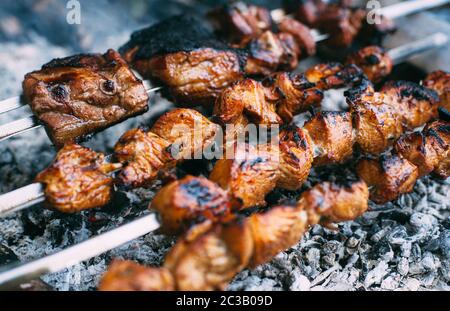 Spiedini di costolette di maiale e pollo su spiedini. Carne alla griglia. Cucina all'aperto. Foto Stock