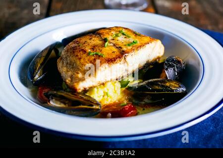 Filetto di pesce fritto con cozze in un piatto sul tavolo. Foto Stock