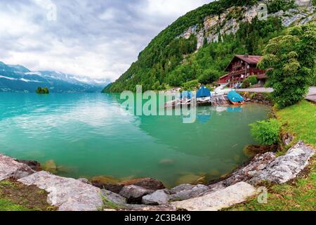 Tradizionale casa di legno e barche sul lago di Brienz nel villaggio svizzero Iseltwald, Svizzera Foto Stock