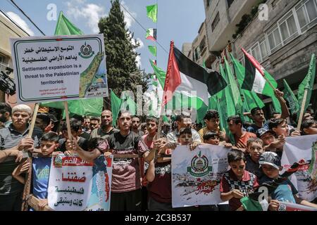 Jabalia, territori palestinesi. 19 giugno 2020. I sostenitori del movimento palestinese di Hamas detengono bandiere e cartelli mentre prendono parte a una marcia di protesta al campo profughi di Jabalia, nel nord della striscia di Gaza, contro il piano di annessione israeliano che occuperà circa il 30% dell'area della Cisgiordania. Il piano di annessione darebbe a Israele il controllo sui controversi insediamenti ebraici in Cisgiordania e sulla strategica Valle del Giordano. Credit: Mohammed Talatene/dpa/Alamy Live News Foto Stock