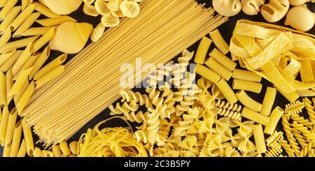 Panorama della pasta italiana, piatto di vari tipi di pasta, sparato dall'alto su sfondo nero Foto Stock