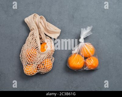 Arance frutti nel sacchetto di plastica e arance di tessili borsa a rete su sfondo grigio. Vista superiore piatta o laici. Rifiuti Zero, i rifiuti alimentari concetto. Foto Stock