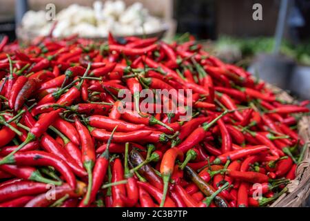 Chilis caldo rosso per la vendita immagazzinato in un grande arco tondo di vimini su un mercato di strada in Cina Foto Stock