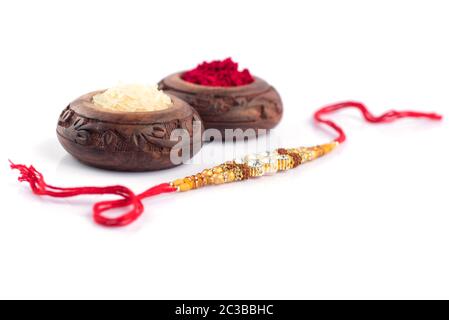 Raksha Bandhan sfondo con un elegante Rakhi, grani di riso e Kumkum su uno sfondo bianco. Un tradizionale indiano fascia da polso che è un simbolo di lo Foto Stock