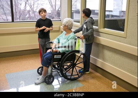 Austin Texas USA, febbraio 11 2014: I nipoti di otto e nove anni visitano la loro nonna in sedia a rotelle in ospedale. ©Marjorie Kamys Cotera/Daemmrich Photography Foto Stock