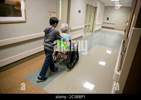 Austin Texas USA, febbraio 11 2014: Il nipote di nove anni spinge la nonna lungo il corridoio mentre la visita in ospedale. ©Marjorie Kamys Cotera/Daemmrich Photography Foto Stock